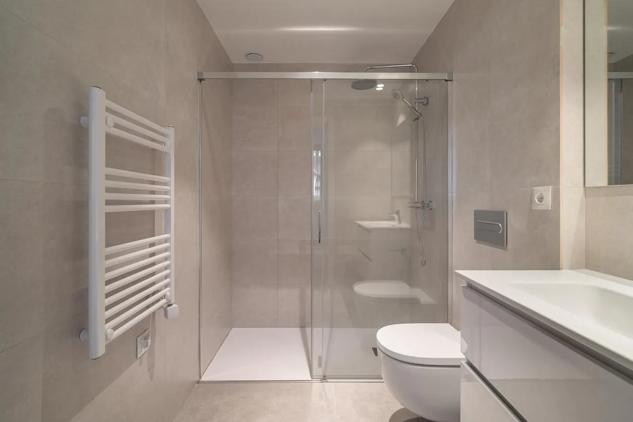 Refurbished bathroom with a frameless walk-in shower, grey large-format tiles and a wall-hung toilet
