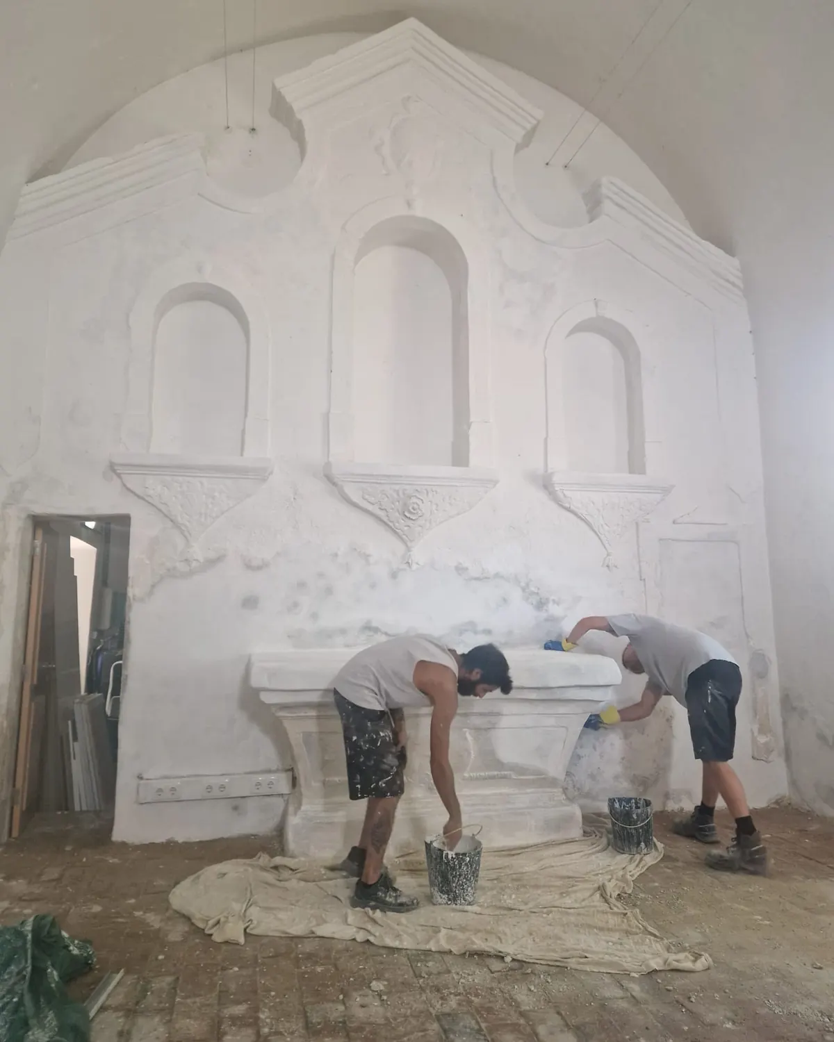 Two Shadowbrook craftsmen restoring the carved stone altarpiece of a sixteenth-century chapel in Lagos