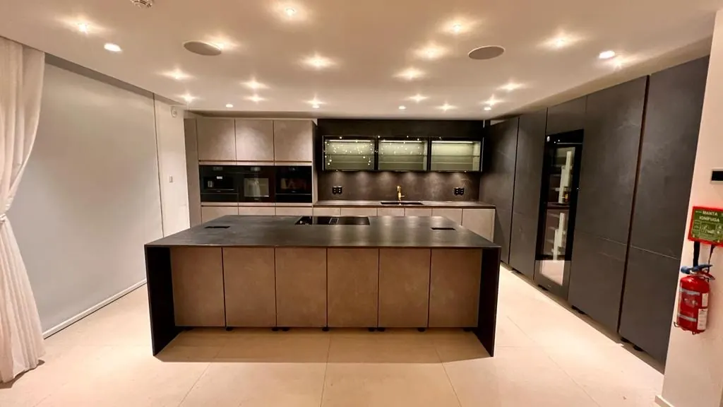 Refurbished kitchen in Lagos with a bronze-toned island, dark stone worktop and integrated tall units