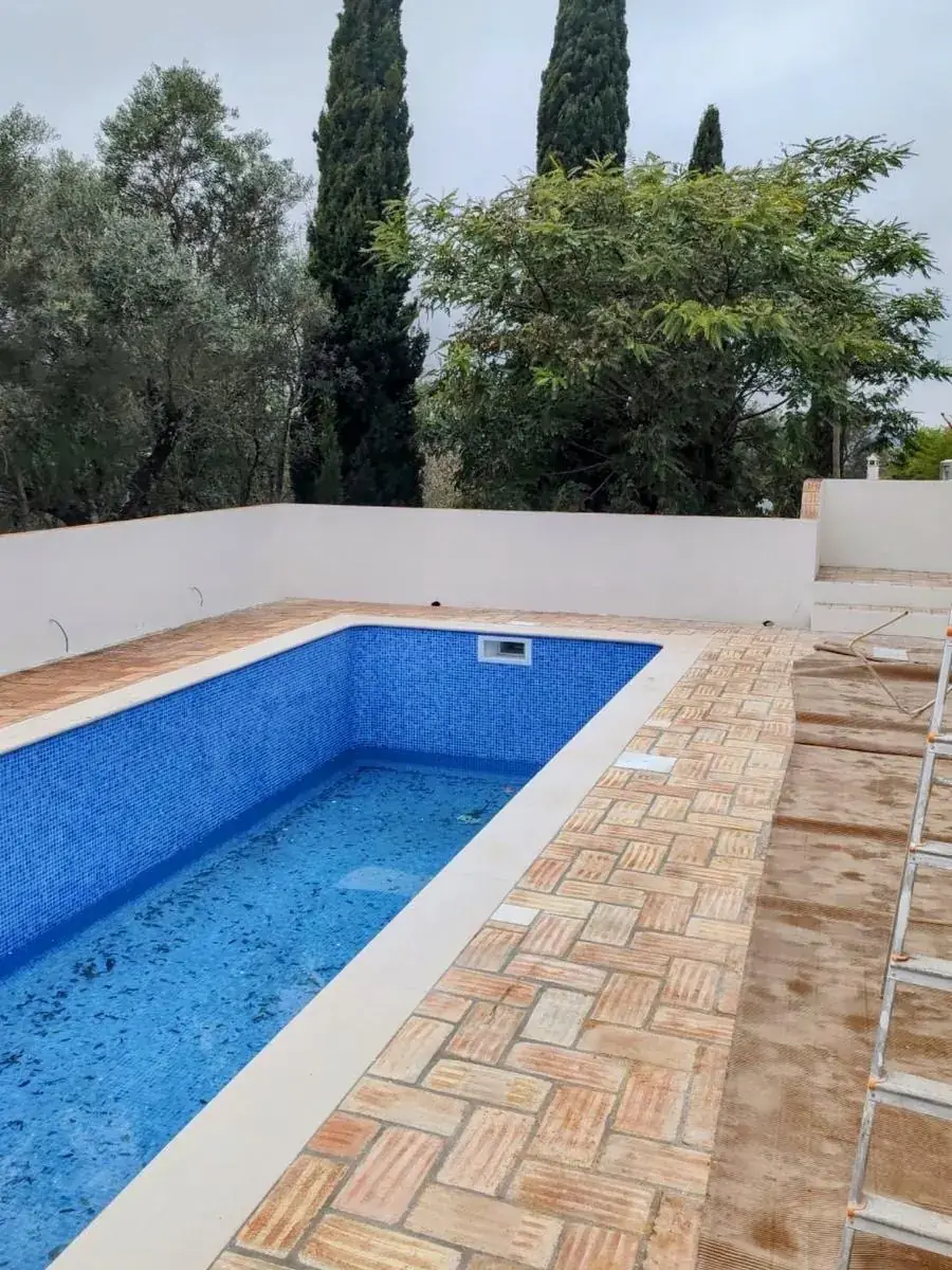 Finished pool with a blue mosaic lining and terracotta herringbone paving, São Brás de Alportel