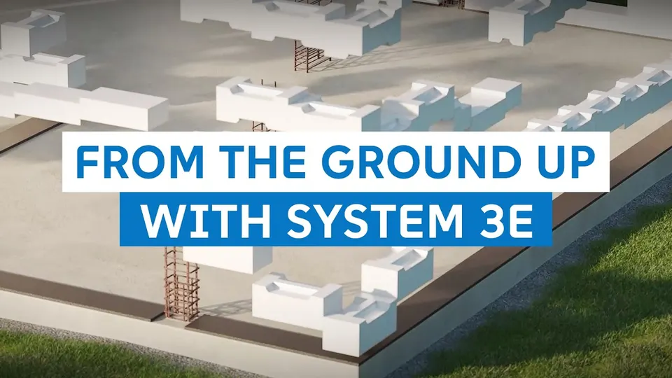 Still from the SYSTEM 3E build video: perlite wall elements being stacked on site