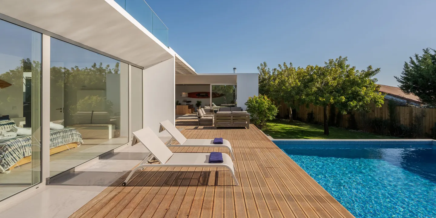Contemporary single-storey villa with floor-to-ceiling glazing, a timber pool deck and a garden in the Algarve sun